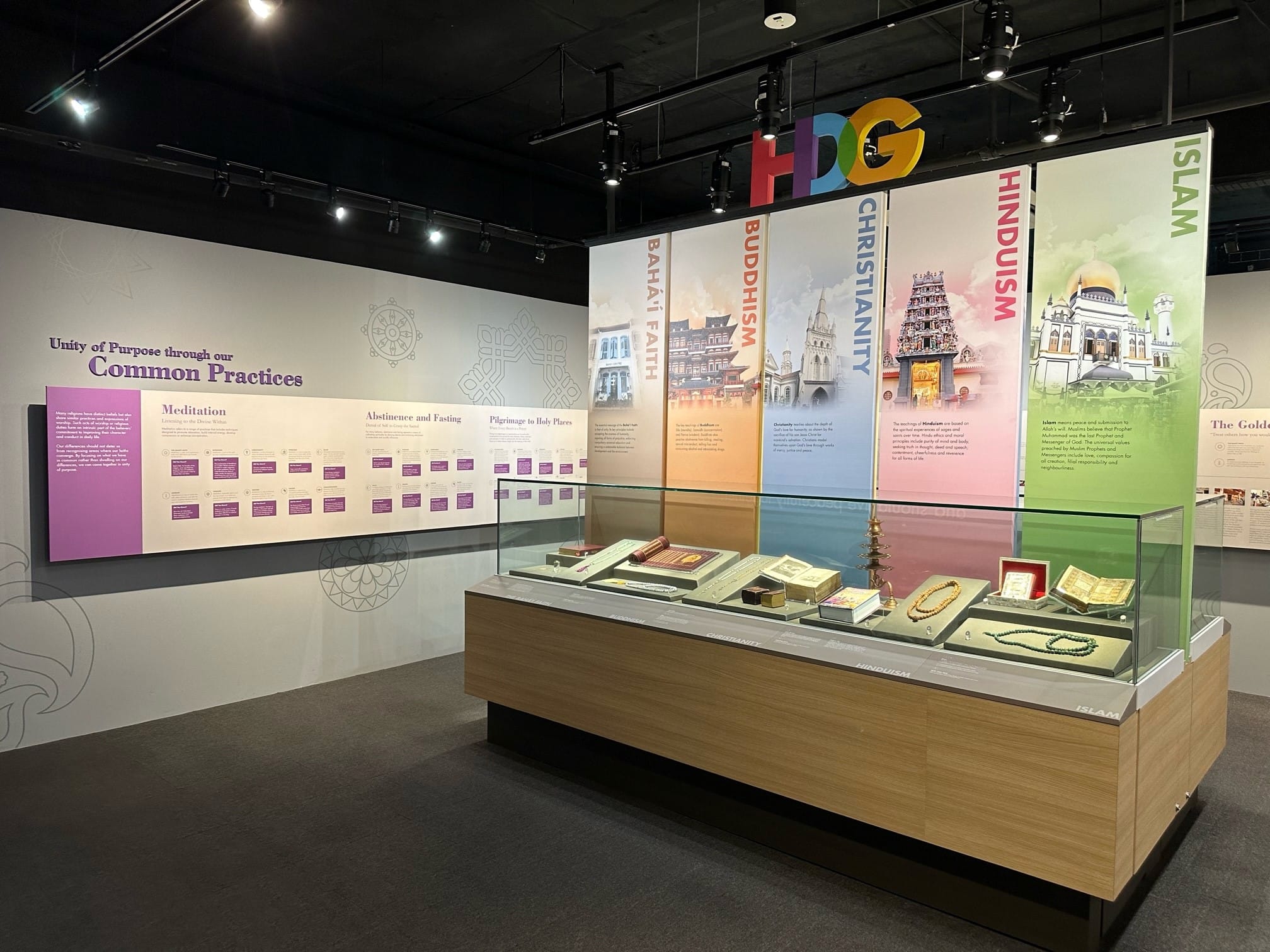 Museum exhibit on world religions featuring panels for Islam, Hinduism, Christianity, Buddhism, and Bahai Faith, with a display case of religious artifacts.